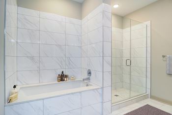 A bathroom with a marble tile wall and a glass shower door.